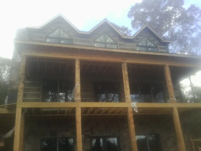 Dormers and porch framing on a large log home under construction — Roof Coating work by our crew in Roy